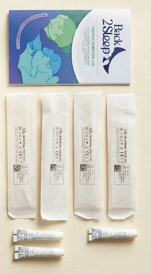 Back2Sleep Snorekit unpacked flat lay — instruction booklet on top, 4 sealed sterile sachets (sizes S, M, L, XL), and 3 lubricant gel tubes — everything included in the kit, on a warm cream surface.